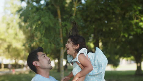 Glücklicher-Asiatischer-Vater,-Der-Kleine-Tochter-Draußen-Hochwirft