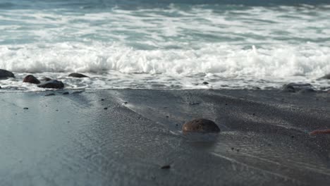 Sea-waves-washing-sandy-beach-and-small-pebbles-on-it,-low-angle-view