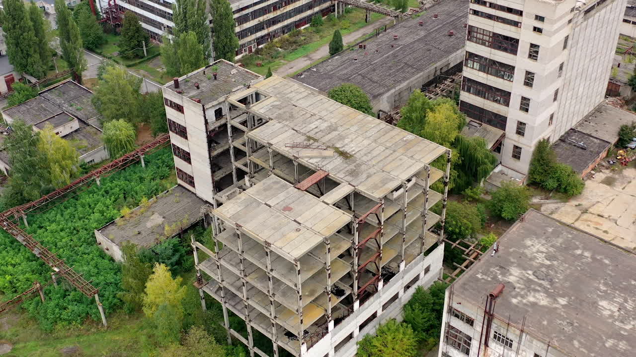 Unfinished old building without windows on a factory. Abandoned territory of industrial plant with empty buildings and warehouses. Aerial view.
