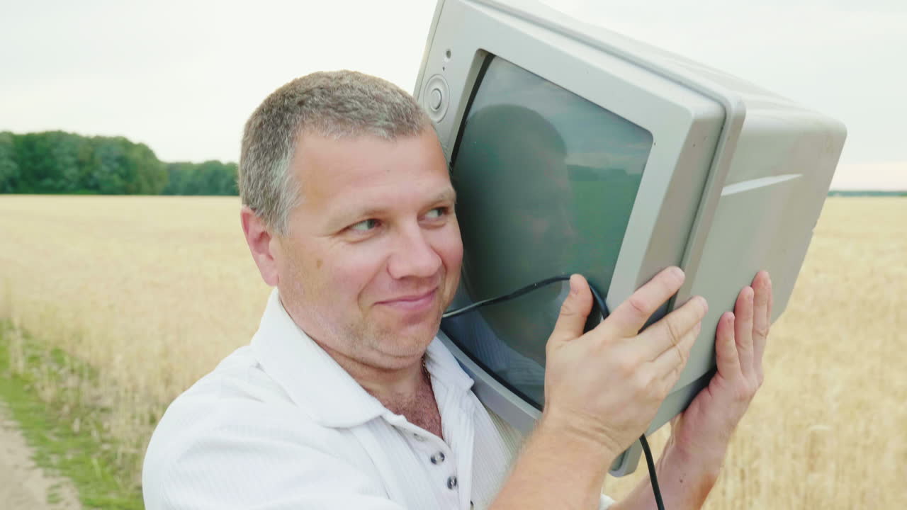 un hombre genial de mediana edad lleva un viejo televisor en el hombro