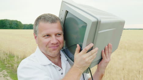 un hombre genial de mediana edad lleva un viejo televisor en el hombro