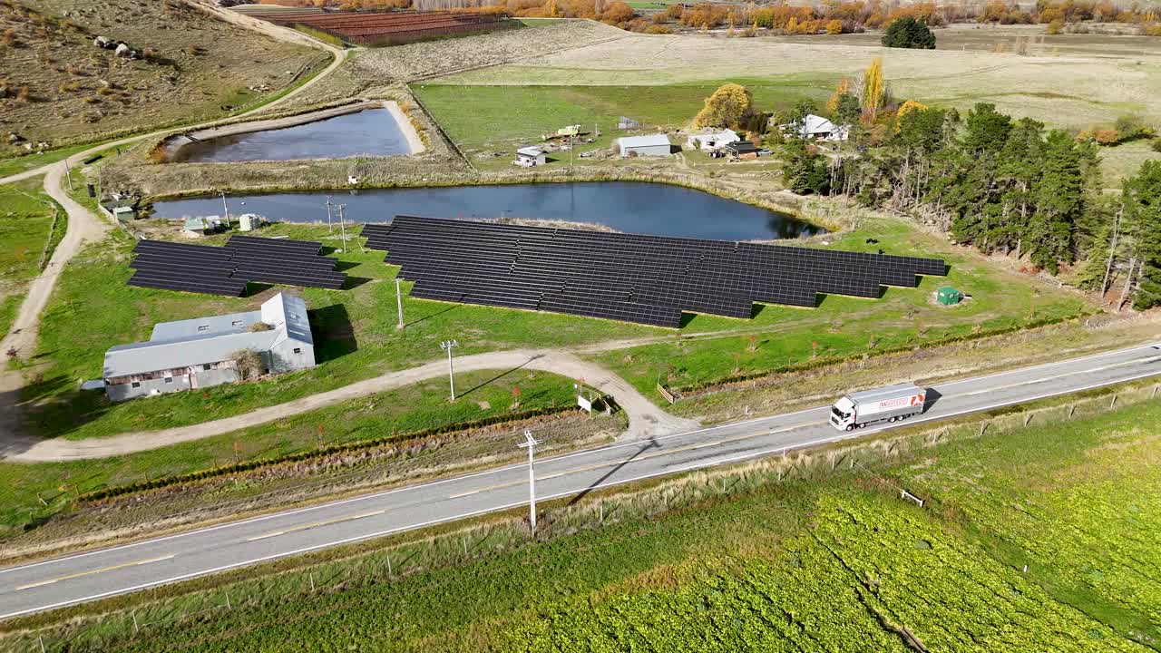 Drone footage captures a solar farm with panels and surrounding landscape in Cromwell, New Zealand, under clear daylight