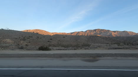 driving in the mojave desert with mountains in background sunset time