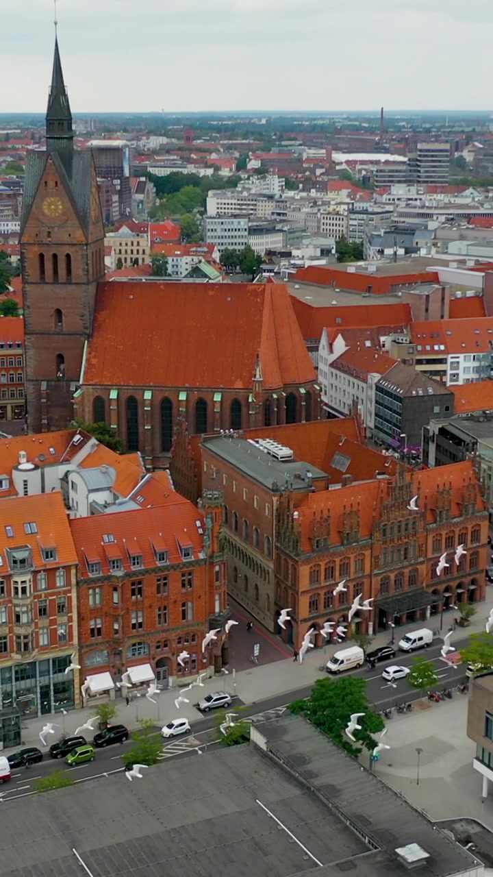 Ripresa aerea verticale cinematografica con drone del centro di Hannover, con la storica Chiesa del Mercato e tetti di tegole rosse. Perfetto per contenuti di viaggio sui social media e storie di sostenibilità urbana.