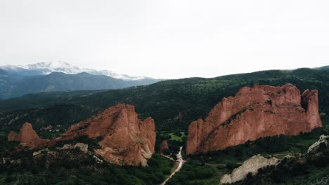 Drone-shot-approaching-Garden-of-the-Gods-to-reveal-the-lush-green-valley-the-rock-formation-sits-in