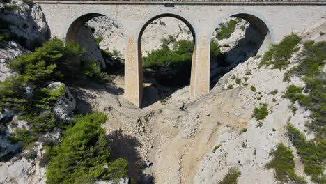 Rückzug-Der-Drohne-Aus-Historischen-Hohen-Bögen,-Während-Entdecker-An-Der-Küste-Frankreichs-Wandern