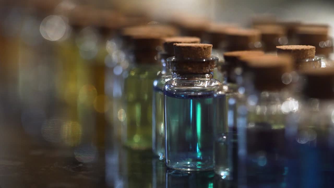 Small glass bottle row blue liquid vial picked up with two fingers macro