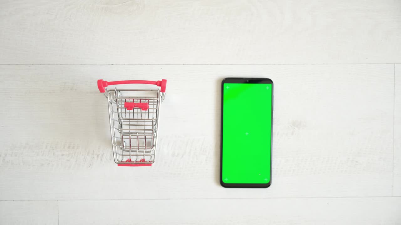 un teléfono con una pantalla chromakey verde y un carrito de compras en un fondo blanco. vista desde la parte superior del teléfono inteligente