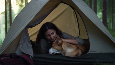 woman and dog inside a tent while camping in the woods