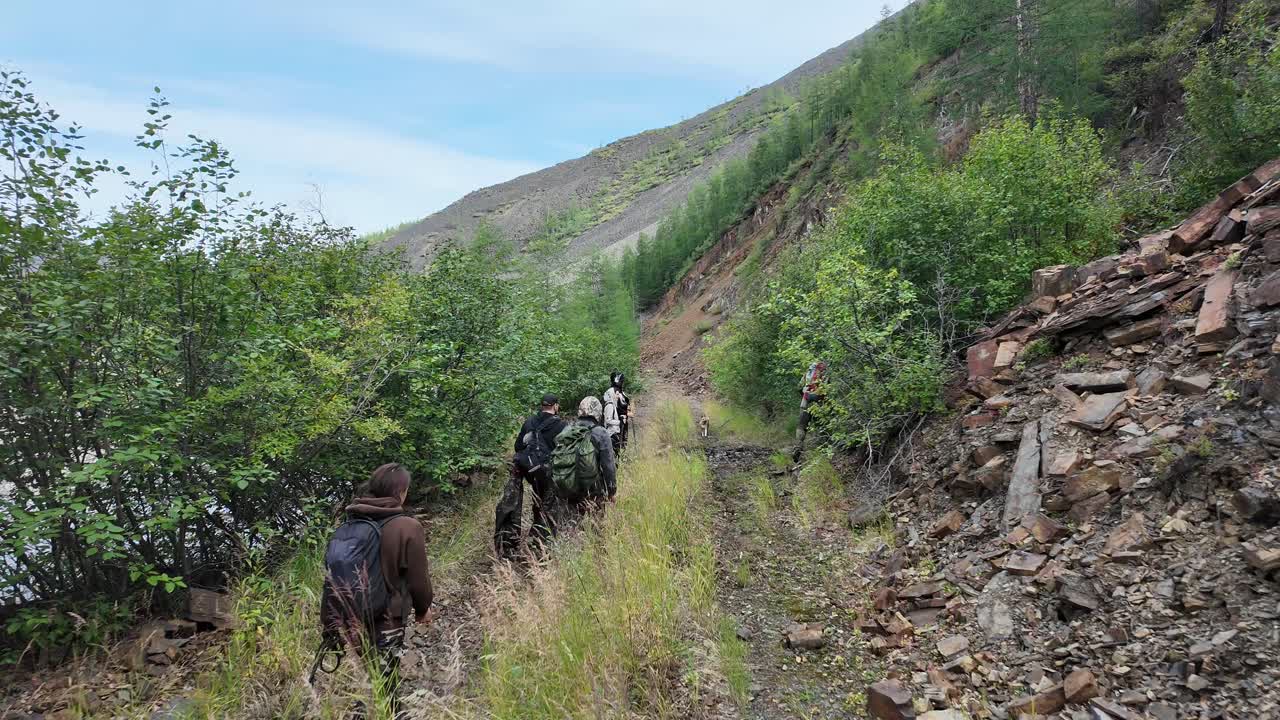 A group embarks on a breathtaking trek through Yakutia's rugged landscape, surrounded by vibrant foliage and natural beauty.