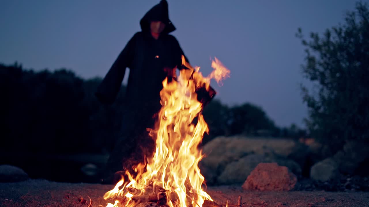 Old evil witch by fire in night forest. Scary Halloween concept