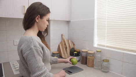 hembra joven usando báscula de cocina para pesar frutas
