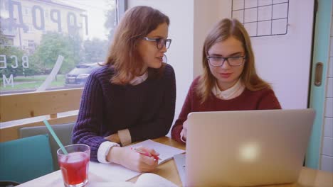 dos mujeres jóvenes estudiando en un café