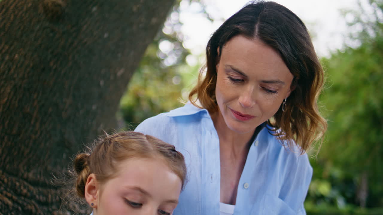 Little kid reading novel spending time with mom together green garden portrait