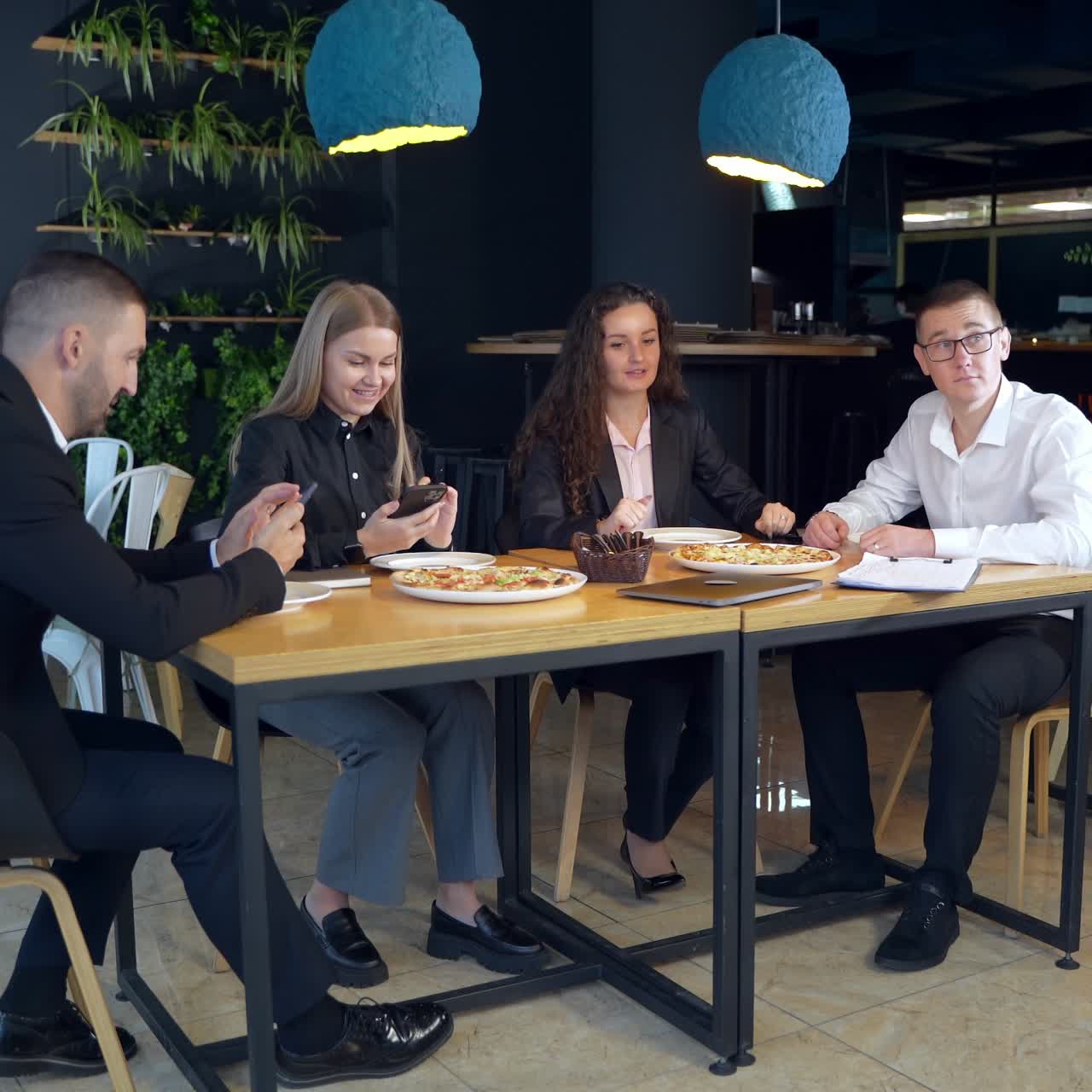 Office team sitting at the table in a café and talking. Lunchtime break for business staff in a friendly atmosphere