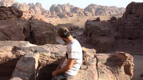 Traveler-caressing-a-cat-in-Petra-valley,-background-mountains,-static-shot