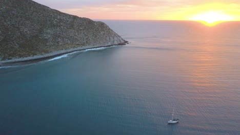aerial view of a sailboat sailing near playa los frailes in baja california with a beautiful sunrise.