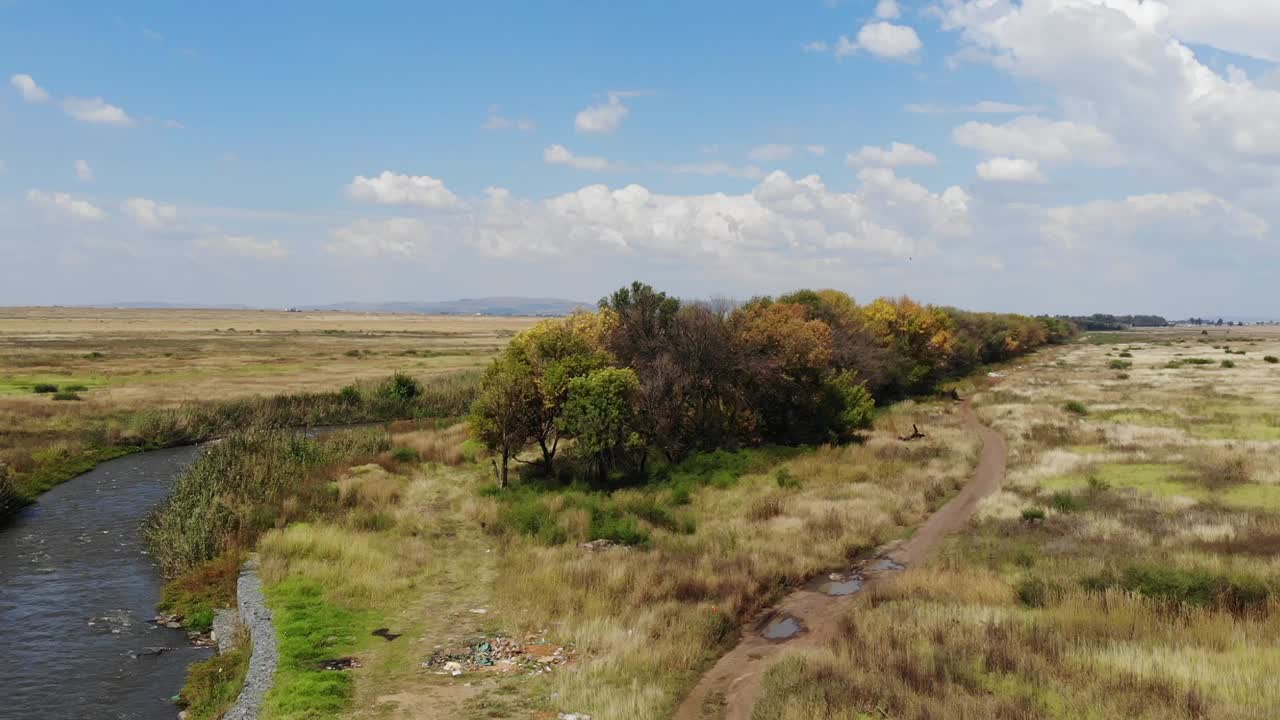 toma aérea de un dron del río que fluye bajo un puente remoto de grava en johannesburgo, sudáfrica