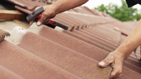 close up of a person carefully putting back roof tiles after adding solar panels mounts