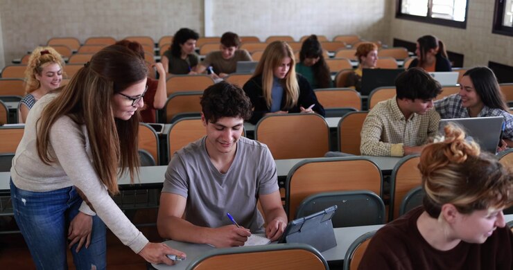 Teacher Assisting Student During University Lecture