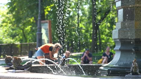 family enjoying a fountain in a park on a sunny day