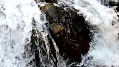 footage of fast water flowing over rocks in the mountain