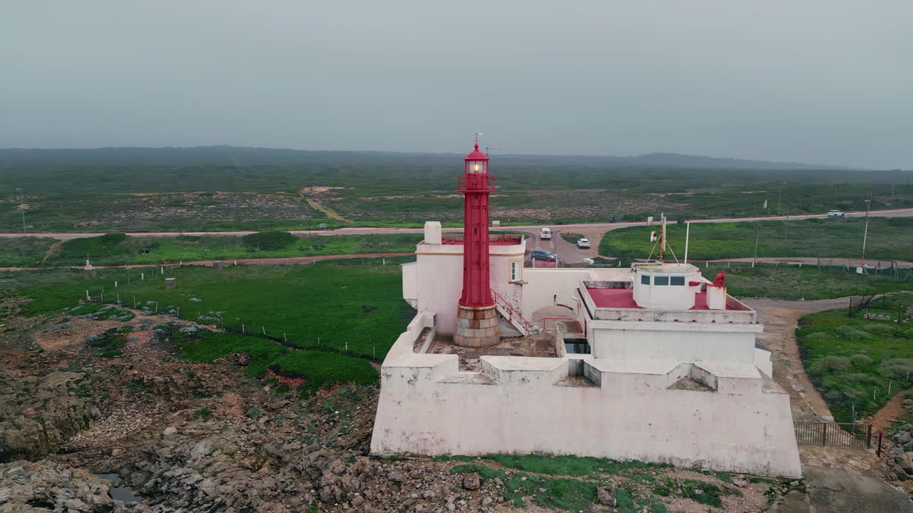 Paesaggio cupo con faro sull'oceano, vista drone. Cielo nuvoloso sulla costa con autostrada