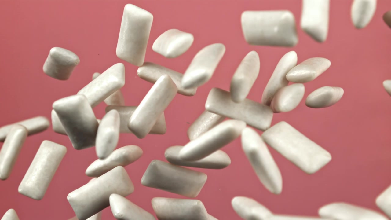 Molti pezzi di gomma da masticare bianca che galleggiano su uno sfondo rosa