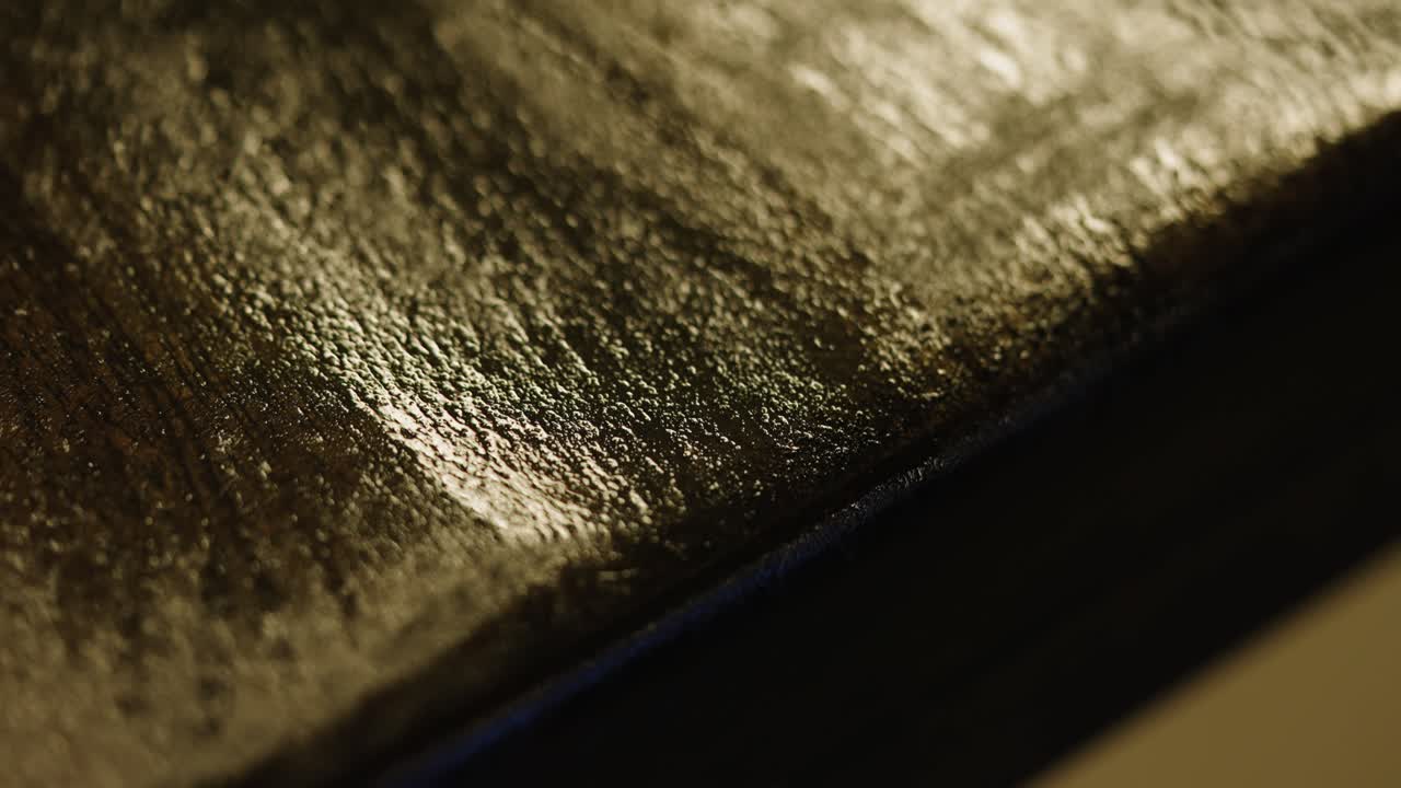 Macro detail black painted wood grain along dining table edge, extreme closeup