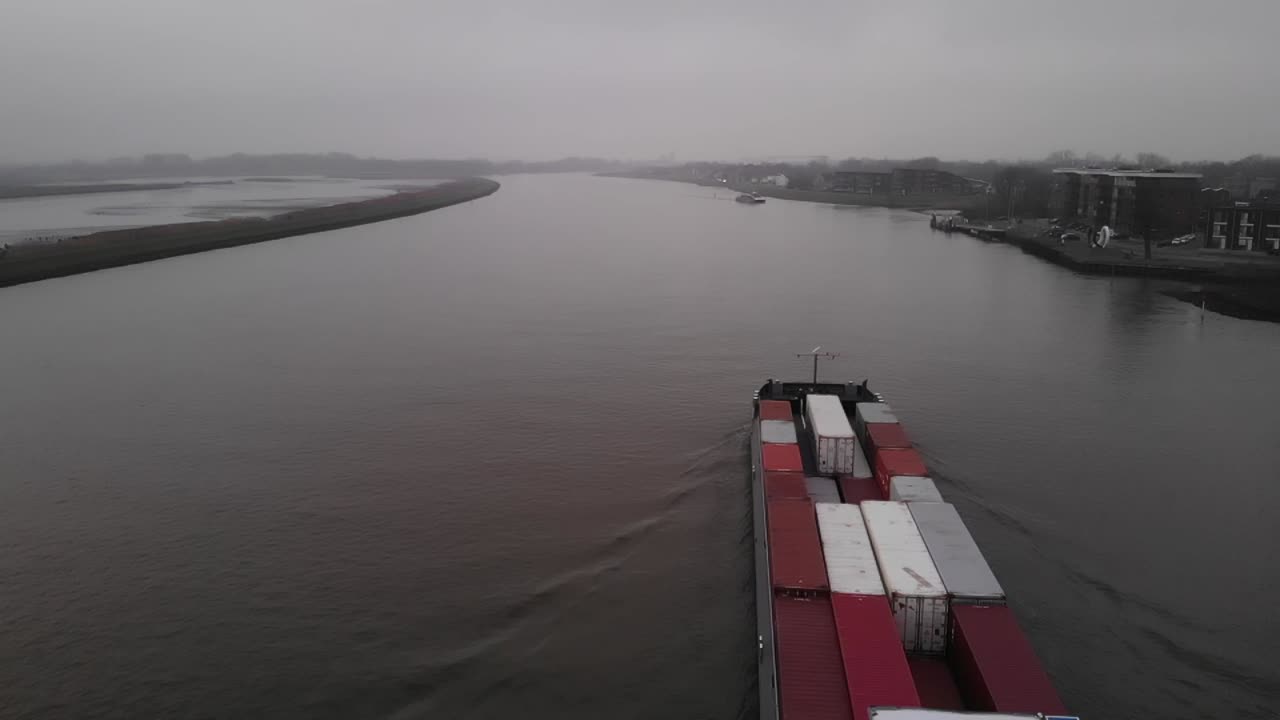 barco de contenedores navegando en un río holandés en un día brumoso