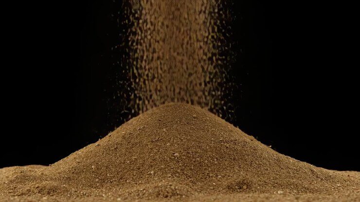 Falling column of sand depositing granules onto central mound at studio surface, widening base