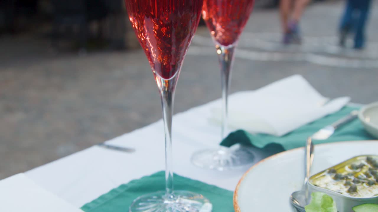 Close-up of fresh salad, bread, and cocktails on outdoor restaurant table, evening natural light