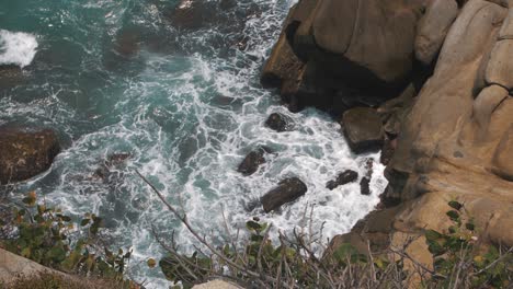 Wellen,-Die-Von-Oben-In-Zeitlupe-Gegen-Felsen-In-Einer-Klippe-Schlagen,-Aufgenommen-Im-Tayrona-Park,-Kolumbien