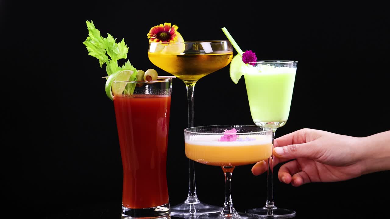 Vibrant cocktails with garnishes are raised in a celebratory toast, set against a sleek black background