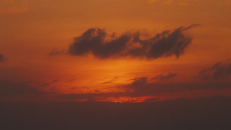 orange warm sunset time lapse with big sun hiding behind clouds