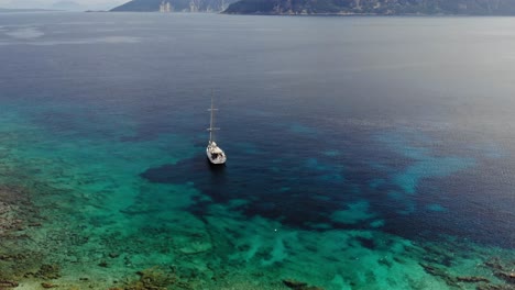 Luftaufnahme-Des-Im-Blauen-Meer-Verankerten-Segelboots-Mit-Korallenriffen-Unter-Dem-Klaren-Wasser