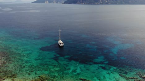 vista aérea del velero anclado en el mar azul con arrecifes de coral bajo el agua clara