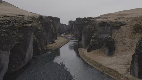 aerial forward between rock walls of fjadrargljufur canyon, iceland