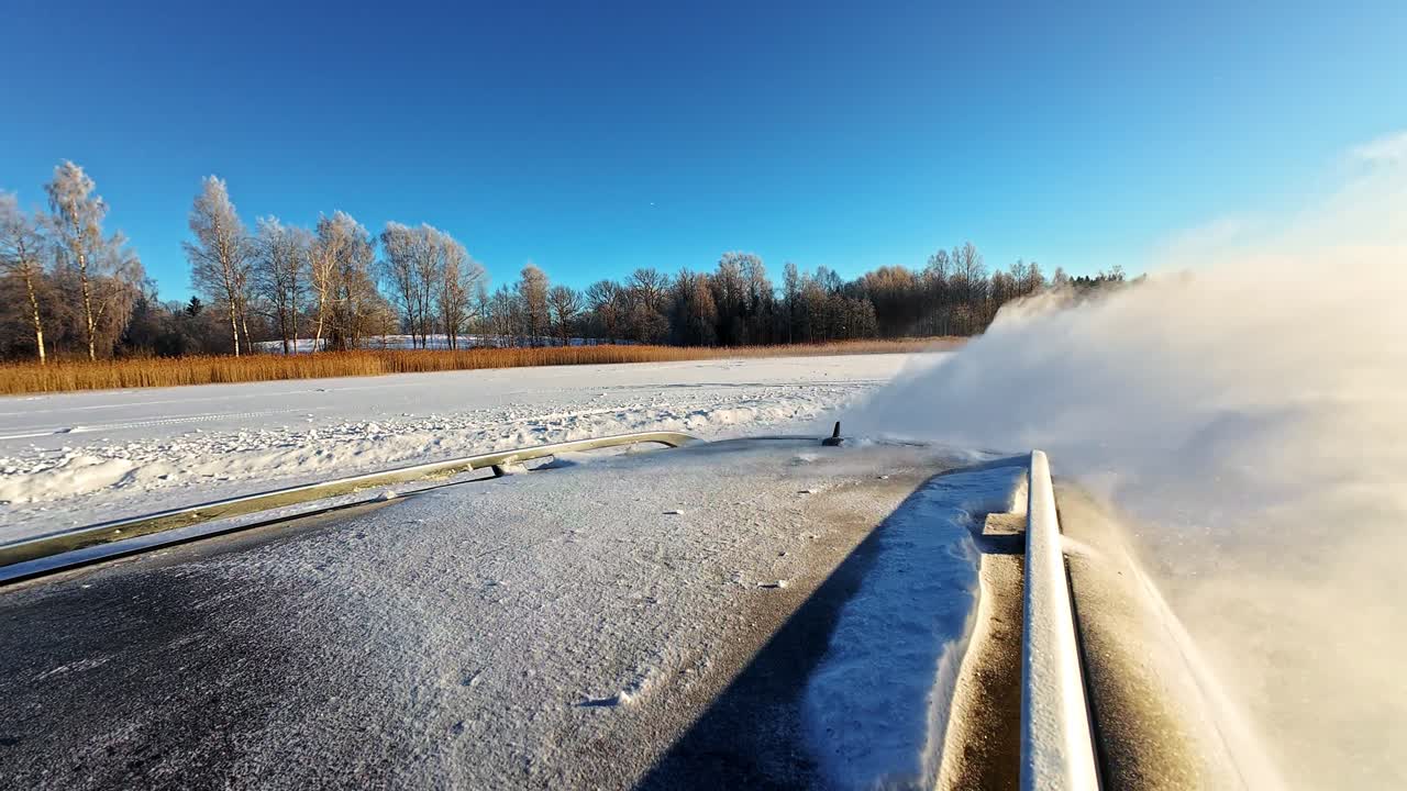 Blick vom Autodach, das sich durch weißen Schneesprühnebel unter strahlend blauem Himmel bewegt