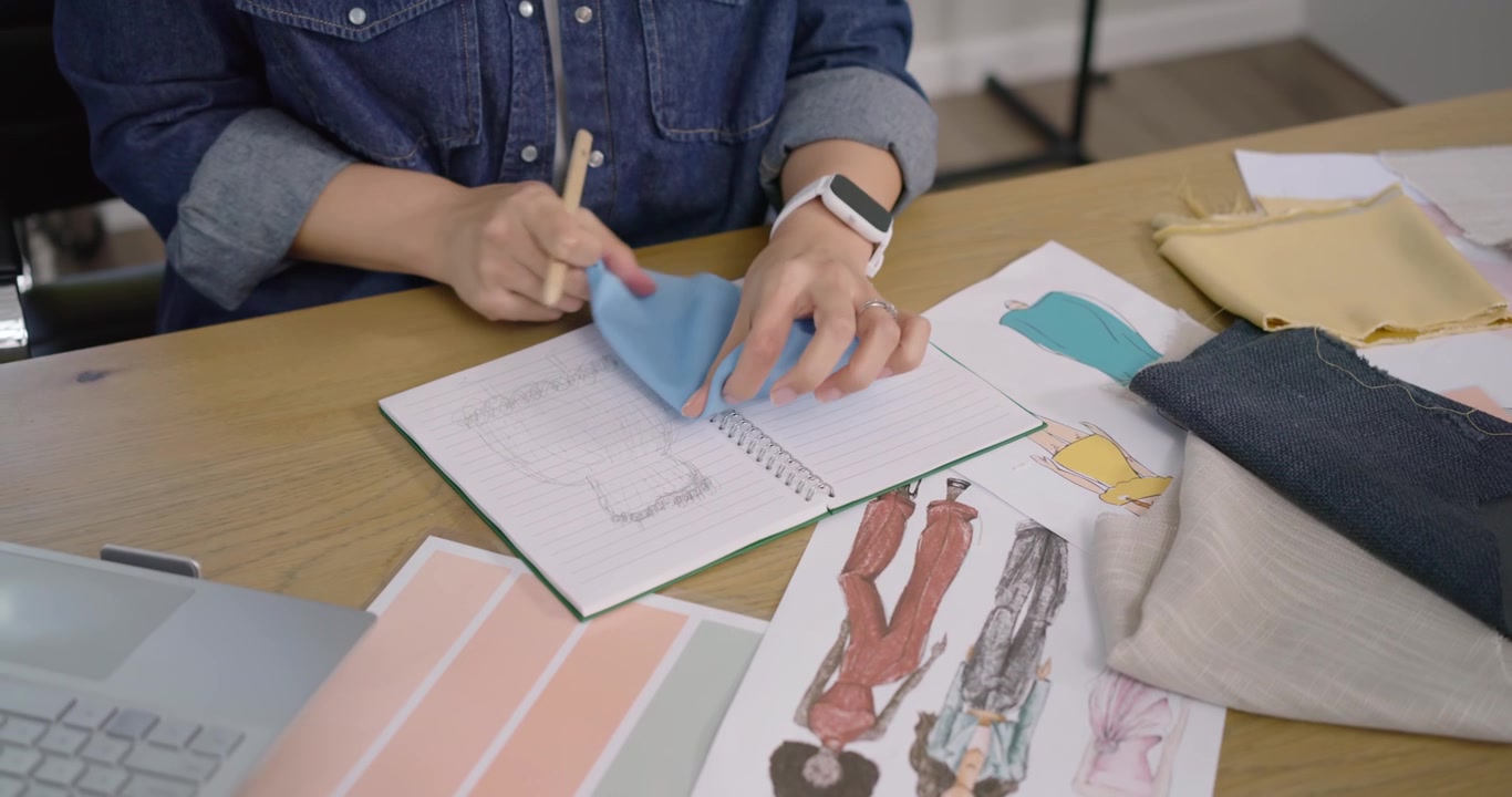 Designer donna che consulta campioni di colore, disegna e confronta tessuti, finalizzando il progetto alla scrivania