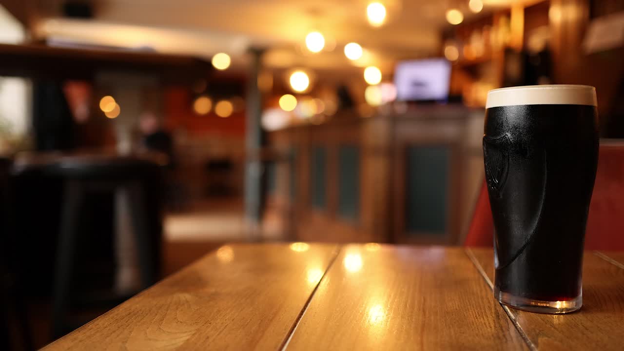 한 남자가 한 맥주를 마시며 술집을 향해 걸어가고 있다.