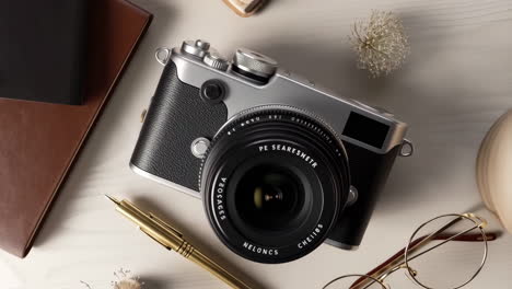 overhead view of a classic-style camera, pen, and eyeglasses on a desk