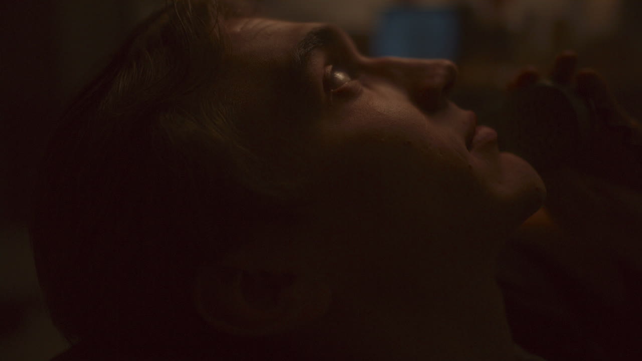 Young Man Leaning Back on Couch, Talking on Vintage Phone in Soft Backlight