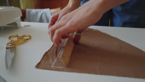 hands of seamstress drawing on fabric with chalk