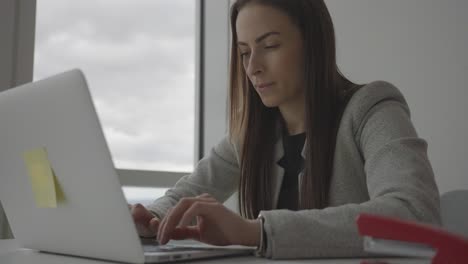primer plano de una joven empresaria satisfecha que trabaja en una laptop en la oficina corporativa