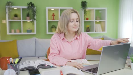 una estudiante universitaria viene felizmente a su escritorio y comienza a estudiar.