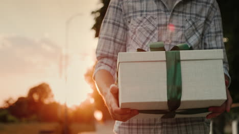 Ein-Mann-Trägt-Eine-Schön-Verpackte-Kiste-Mit-Einem-Geschenk-Und-Geht-In-Der-Sonne-Die-Straße-Entlang-2