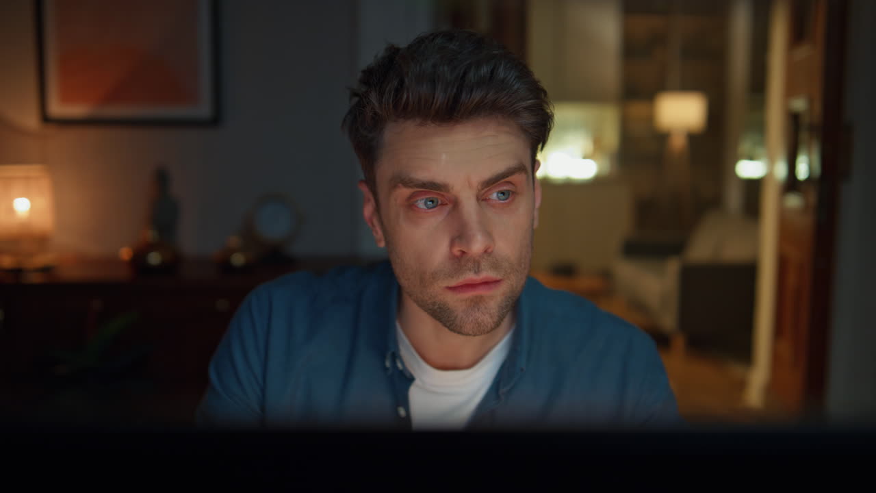 Serious man staring pc working late in home closeup. Guy reading presentation