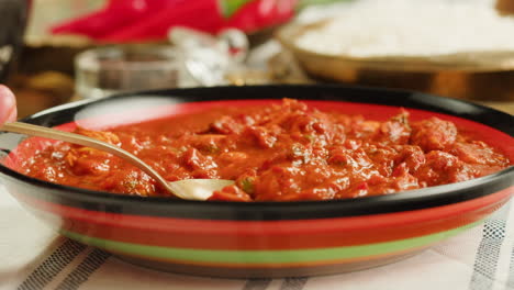 close-up view of a delicious spicy curry served in a colorful bowl with a spoon, ready for a tasty meal.