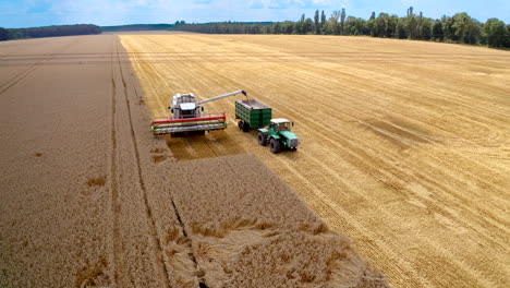 combine harvester agriculture machine with tractor. aerial shot of combine loading off corn grains into tractor trailer